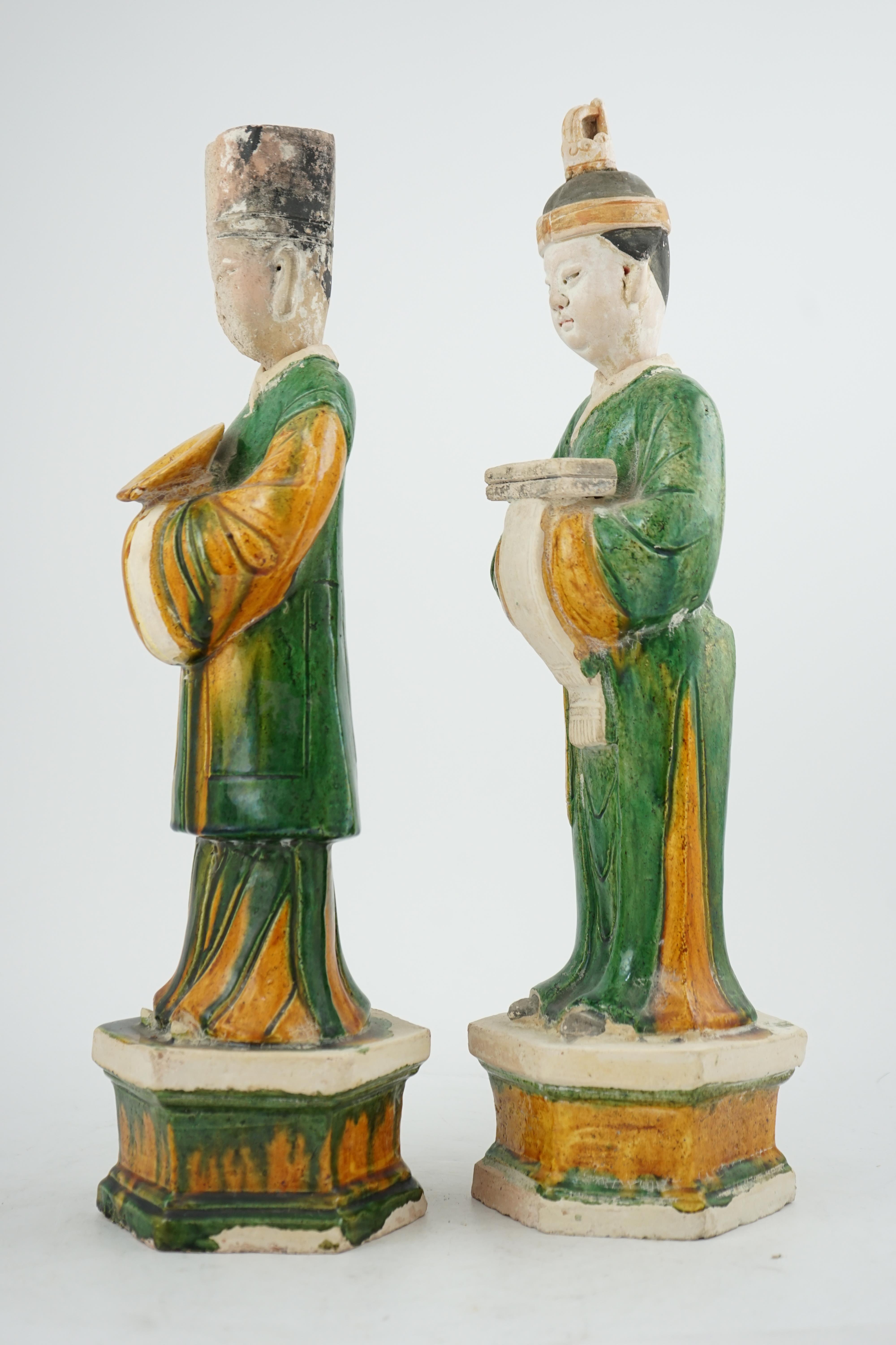 Two tall Chinese sancai figures of attendants, Ming dynasty, the male figure holding a dish and the female figure a box, each standing on a hexagonal base, largest 47cm high. Condition - some wear to face